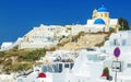 Details of architecture of white houses and hotels with tourists in rooms against the rocks, Santorini, Greece Royalty Free Stock Photo