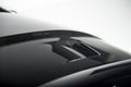 Details of a black sportscar and a white wall