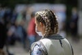 Details with the braids of a blonde woman dressed in Romanian traditional clothing and wearing a Covid-19 mask