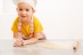 Details of children`s hands kneading dough. Cheerful cook child boy in a cap prepares burritos Royalty Free Stock Photo
