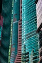 Details of close standing downtown buildings. Vertical lines, rhythm, reflections, cyan and reddish colors. Concept of