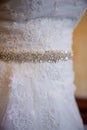 The details close up a of a white wedding dress. Sparkling belt with rocks and white embroidered flowers. Royalty Free Stock Photo