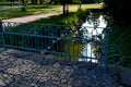 Details of the edge of the pond with paved banks flat stones. curved shape. the path is lined with weeping willows and the sluice Royalty Free Stock Photo