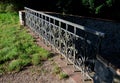 Details of the edge of the pond with paved banks flat stones. curved shape. the path is lined with weeping willows and the sluice Royalty Free Stock Photo