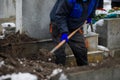 Details of a gravedigger covering a tomb with dirt with a shovel during a burial ceremony on a cold and snowy winter day Royalty Free Stock Photo