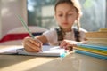 Details: Hand of schoolgirl, first grader holding pencil, making notes on copybook while learning writing at classroom