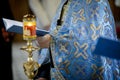 Details with the hand of an Orthodox priest holding a Bible and a cross during an Orthodox Baptism.