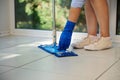 Details: hands in blue rubber work gloves of a housewife mopping the floor in the house. Housekeeping. Cleaning. Chores