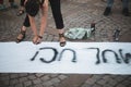 Details with the hands of a young woman writing with a black paint spray a feminist message on a piece of whitee cloth