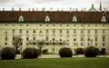 Details of Hofburg Imperial Palace building architecture with lots of windows and doors facade in pastel color and grass field Royalty Free Stock Photo