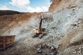 details of industrial track type excavator digging and loading ore in a dumper truck