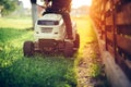 Details of landscaping and gardening. Worker riding industrial lawnmower
