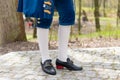 Details of a man dress in a baroque costume. White stockings and black shoes