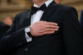 Details with a man in tuxedo holding his hand on his hearth while hearing the national anthem