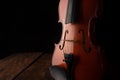 Details of an old and beautiful violin on a rustic wooden surface and black background, low key portrait, selective focus Royalty Free Stock Photo