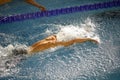 Details with a professional male athlete swimming in an olympic swimming pool butterfly style