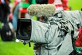 Details of a professional television camera, with rain cover, live broadcasting a soccer game