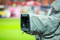 Details of a professional television camera, with rain cover, live broadcasting a soccer game