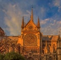 Details of the southern facade of Notre Dame de Paris Cathedral facade with the rose window and ornate spires in the warm light of