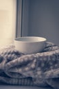 Details of still life in the home interior. Sweater, cup, wool, cozy, book, candle. Moody. Cosy autumn winter concept. Royalty Free Stock Photo