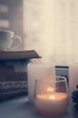 Details of still life in the home interior. Sweater, cup, wool, cozy, book, candle. Moody. Cosy autumn winter concept. Royalty Free Stock Photo