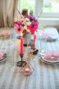 Details of summer festive table with candles and seasonal flowers. Royalty Free Stock Photo