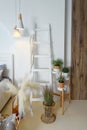 Details of a trendy bedroom with artificial flowers, a wooden staircase, wicker elements and a wooden wall. Royalty Free Stock Photo