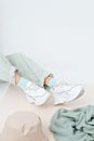 Details of trendy casual spring summer fresh outfit. Girl in studio wearing khaki jeans and stylish white sneakers.  Bucket hat Royalty Free Stock Photo