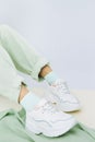 Details of trendy casual spring summer fresh outfit. Girl in studio wearing khaki jeans and stylish white sneakers.  No face. Royalty Free Stock Photo