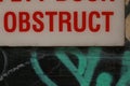 Details of a warning sign on a back entry door in a side alley covered in graffiti, detail showing only the word