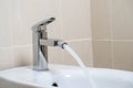 Details of white ceramic bidet with water running from tap in modern bathroom with beige tiles background. Close up Royalty Free Stock Photo