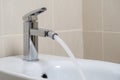 Details of white ceramic bidet with water running from tap in modern bathroom with beige tiles background. Close up Royalty Free Stock Photo