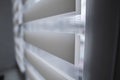 Details of white fabric roller blinds on the white plastic window in the living room. Close up on roll curtains indoor. Royalty Free Stock Photo