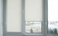 Details of white fabric roller blinds on the plastic window with wood texture in the living room. Royalty Free Stock Photo