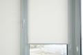 Details of white fabric roller blinds on the plastic window with wood texture in the living room. Royalty Free Stock Photo