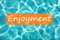 Detal of word `Enjoyment` on swimming pool water and sun reflecting on the surface