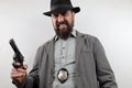 Detective with beard wearing hat and police badge holding gun with angry expression on face. Royalty Free Stock Photo