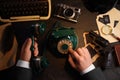 Detective dialing number on vintage telephone at table Royalty Free Stock Photo