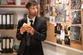 Detective eating hamburger in his office, private detective looking at evidence board and eating fast food, break and Royalty Free Stock Photo