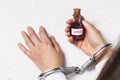 Detention for the illicit sale of toxic drugs. Doctor in handcuffs holding a bottle of virus