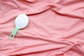 Detergent powder in measuring spoon on pink cloth before washing. Laundry concept