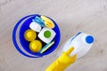 Detergents in plastic bottles, sponges, brush in blue household bucket. Hand in yellow rubber glove. Service concept.