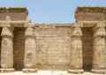 Deteriorating columns  in front of a wall filled with reliefs in the 2nd court of the Mortuary Temple of Ramesses III. Royalty Free Stock Photo