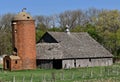 Deteriorating hip roofed barn and brick silo Royalty Free Stock Photo