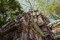 The deteriorating stone tower of Ta Prohm, a significant example of Khmer architecture, attracts the gaze of tourists amidst the