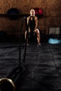 Determinated woman tossing ropes at gym