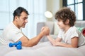 Determination. Cute latin boy and his father having fun together at home while armwrestling lying on the couch Royalty Free Stock Photo