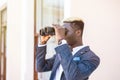 Determined young african american businessman using binoculars in office