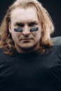 Determined American football player posing with painted face and chewing gum Royalty Free Stock Photo