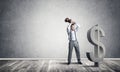 Determined banker man in empty concrete room breaking dollar figure